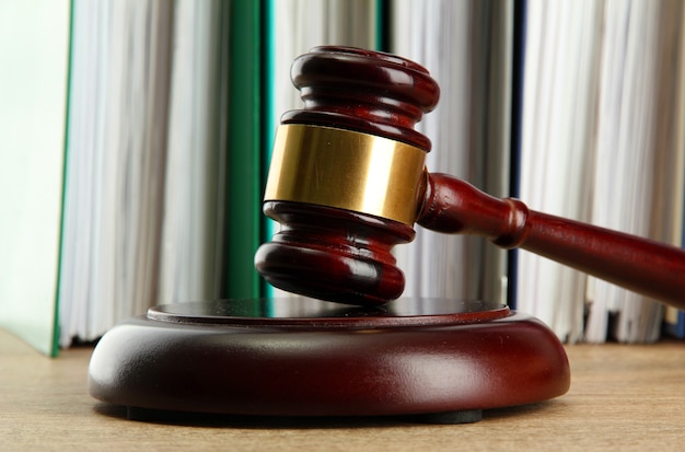 Wooden gavel and folders on wooden table, close up