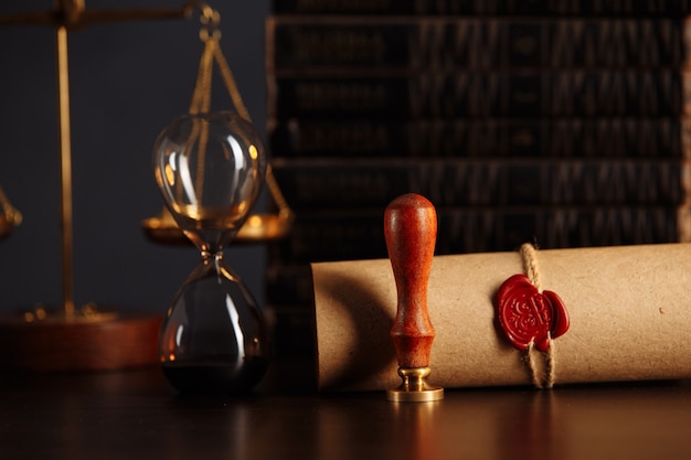 Wooden gavel, hourglass, books and stamp on testament and last will on wooden table. Notary public tools.