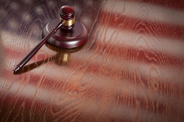 Photo wooden gavel resting on american flag reflecting table