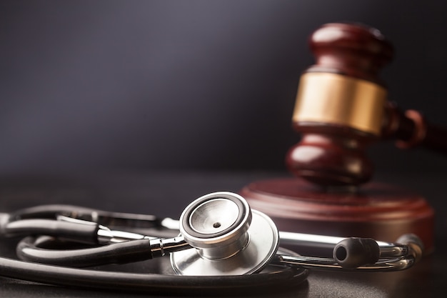 Wooden gavel and stethoscope on background