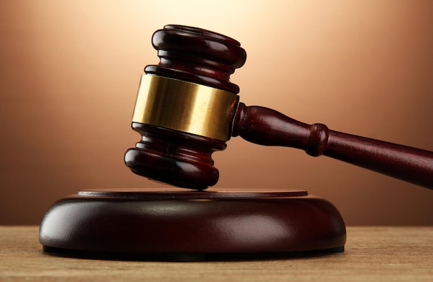 Wooden gavel on wooden table on brown background