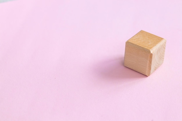 Wooden geometric shapes cube isolated on a pink