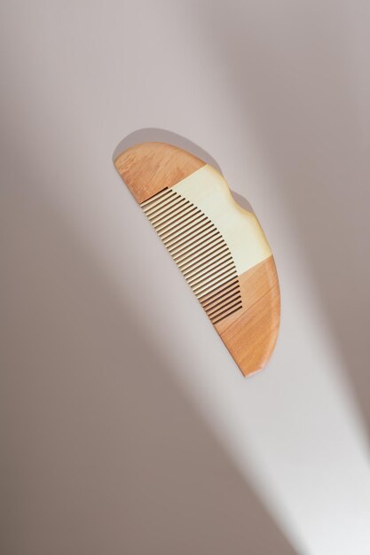 Photo wooden hair comb on a pastel beigr background with gobo shadow trendy catalogue shot