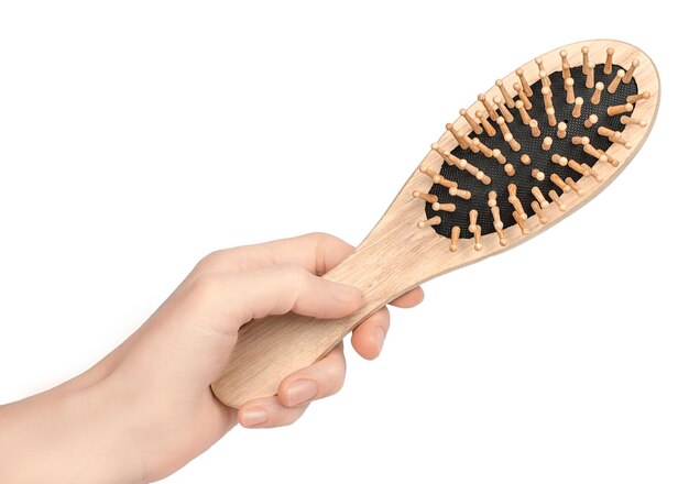 Wooden hairbrush in a female hand on a white background isolate