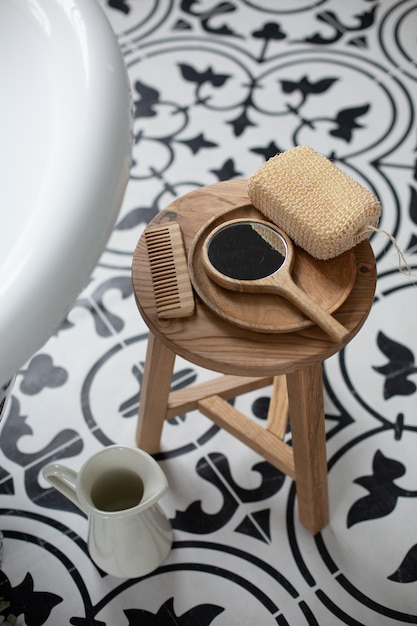 Фото Деревянная расческа, зеркало и губка на стуле в ванной