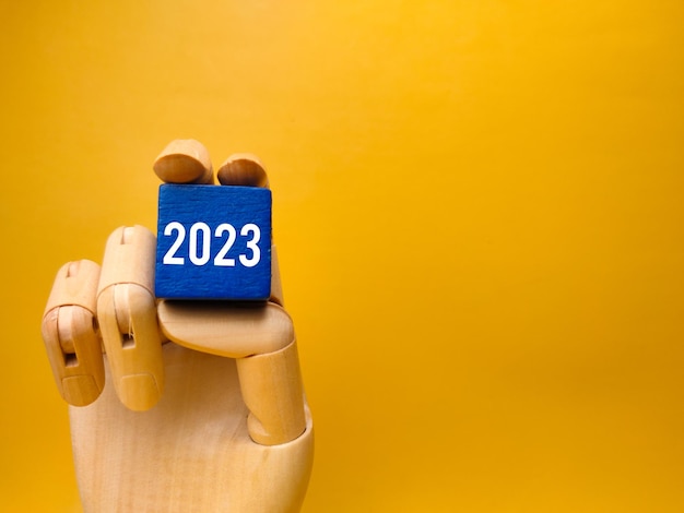 Wooden hand holding colored cube with the number 2023 The concept of happy new year