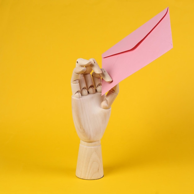 Wooden hand holding pink concert on yellow background