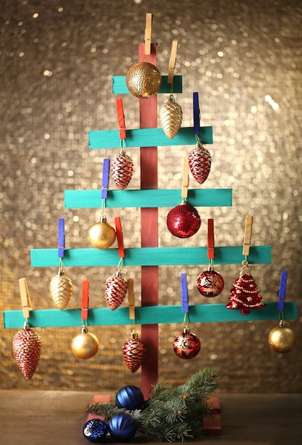 光沢のある背景にクリスマスの装飾が施された木製の手作りモミの木