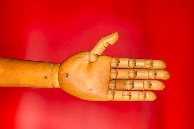 赤い背景に木の手。木製の人間の手 - プロテーゼのクローズ アップ。