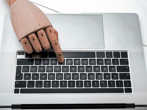 Wooden hand touching computer keyboard