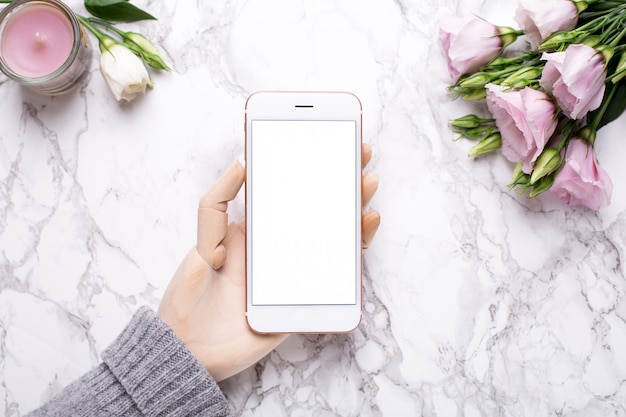 Wooden hand with mobile phone on marble 