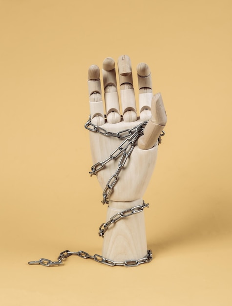 Wooden hand wrapped in a steel chain on a yellow background Censorship imprisonment