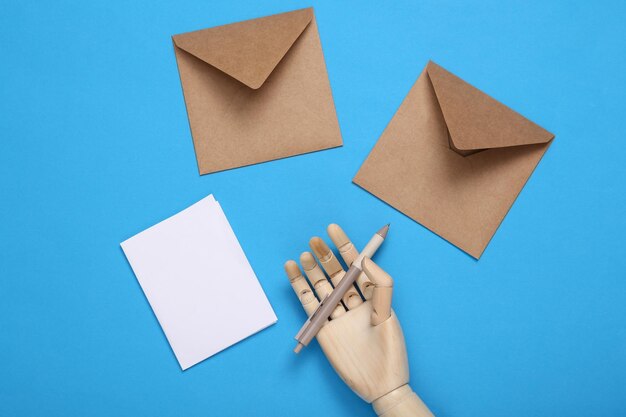 Wooden hand writes a letter on a blue background