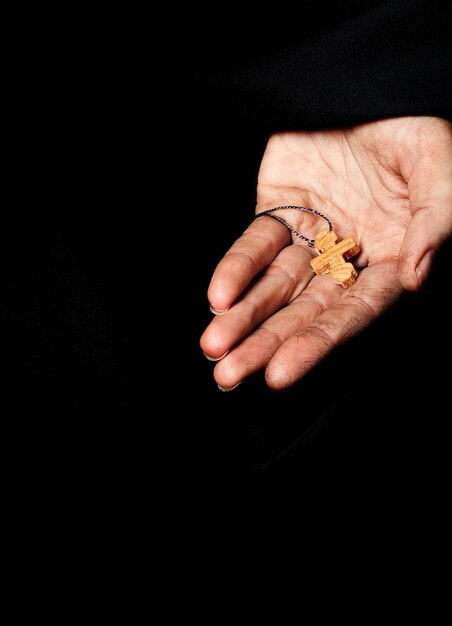 Wooden handmade cross in the palm of a peasant woman. Closeup