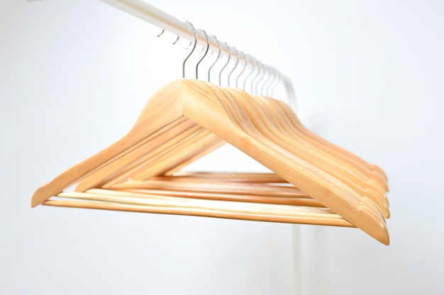 A wooden hanger hangs on a rail isolated with white background.