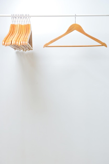 A wooden hanger hangs on a rail isolated with white background.