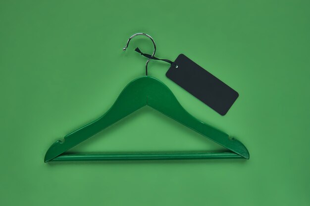 Photo wooden hanger with black paper label isolated on green paper background. seamless pattern mockup tem