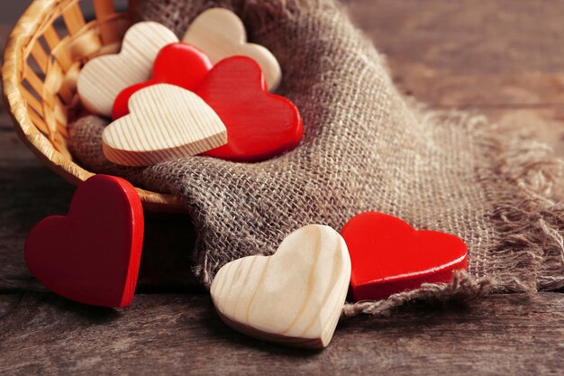 Wooden hearts in wicker basket on rustic wooden background