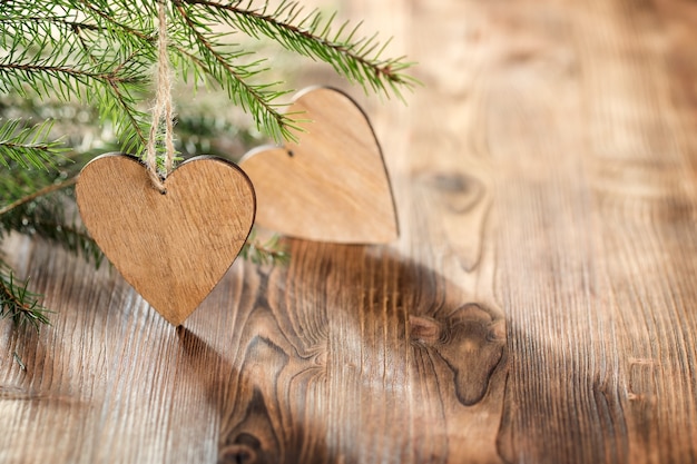 Wooden hearts on wooden background with fir branches