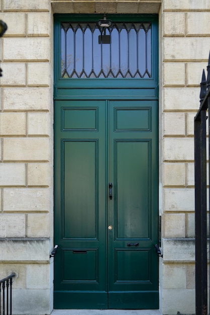 フランスの壁の入り口の都市通りの古典的な石のファサードに緑の木製の高いドア