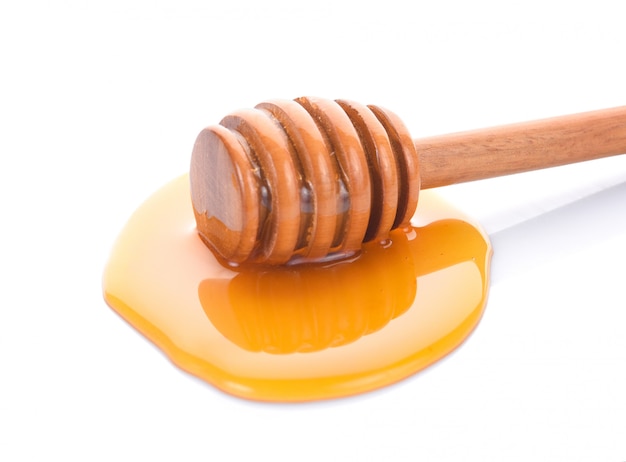 Wooden honey dipper with honey on white background