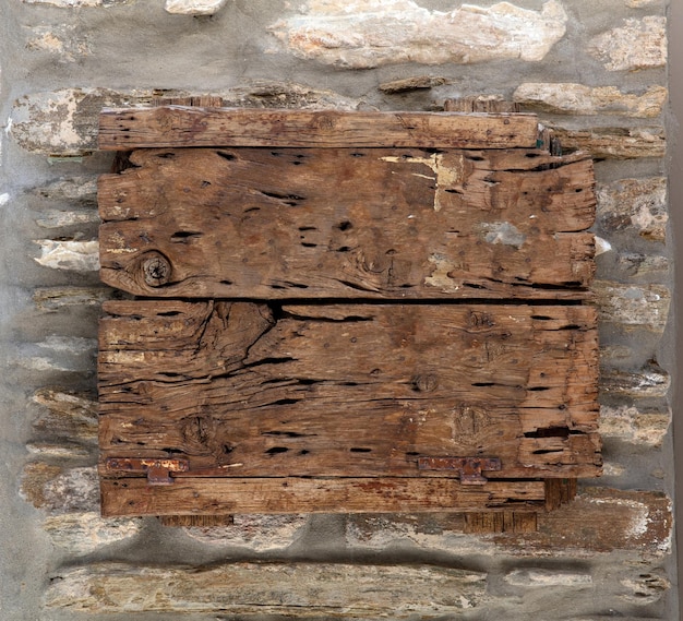 Wooden horizontal empty cracked aged plank on rocky wall background Cyclades Greece Copy space