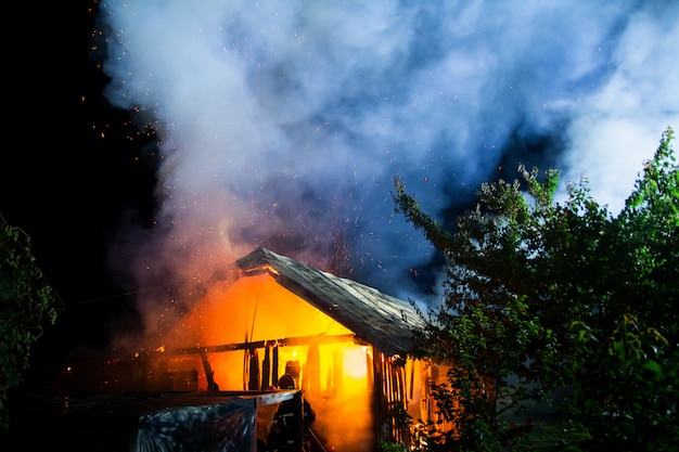 Casa in legno o fienile che brucia sul fuoco durante la notte.