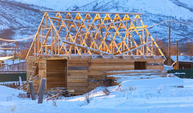 Wooden house under construction in winter