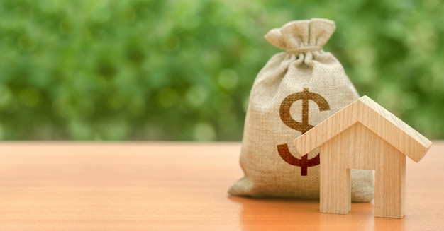 Figurina di casa in legno e borsa di denaro con un simbolo del dollaro. bilancio, fondi sovvenzionati