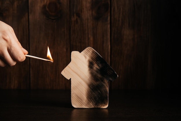 Foto casa in legno e mano con fiammifero