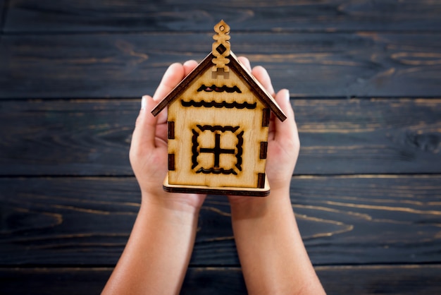 Wooden house in the hands. the concept of buying a home,\
mortgage or loan. view from above.