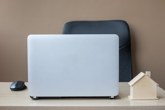 Wooden House model and computer laptop on table