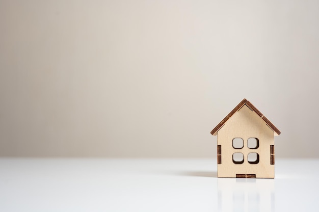 Wooden house model on white table Mini residential craft house construction mortgage real estate Housing and homeownership cost concept purchase and sale of housing copy space