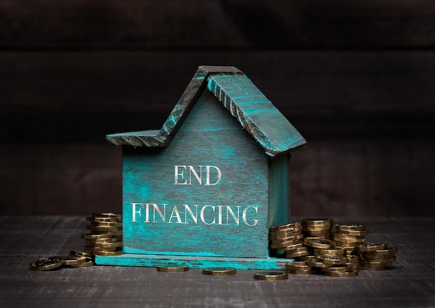 Wooden house model with coins next to it and hand