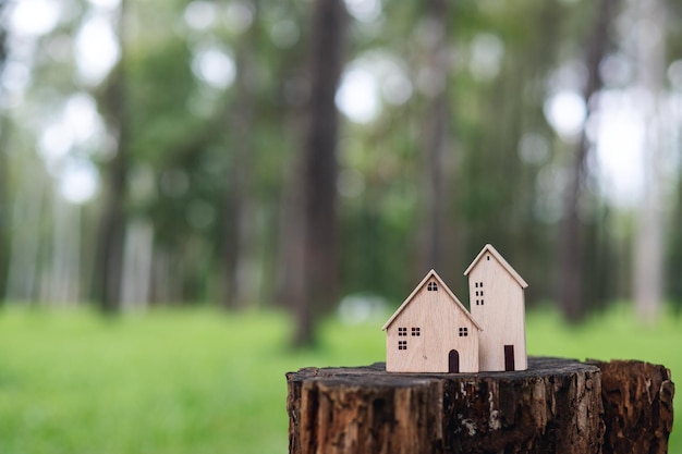 Photo wooden house models on tree stump in the outdoors