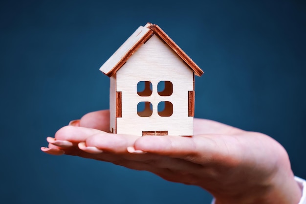 Foto casa in legno nel palmo della tua mano il concetto di acquisto la vendita o l'assicurazione di beni immobili sullo sfondo