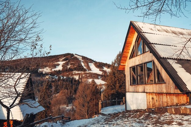 Wooden house at sunset on a background of snowy mountains