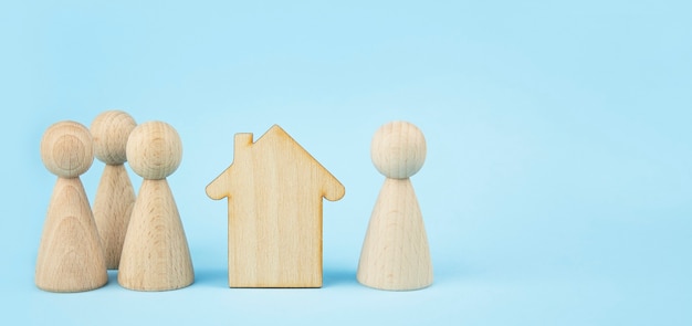 Wooden house and wooden little men on a blue background. Property division . Insurance concept, home purchase. Copy space. Banner.