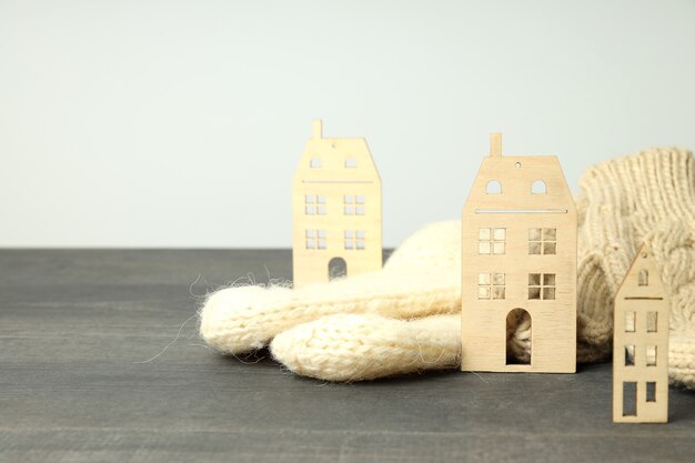 Wooden houses and knitted clothes on gray wooden table.