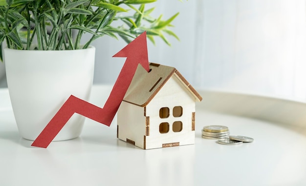 Wooden houses stand in a row from small to large with a red arrow up concept of high demand for real estate increase energy efficiency of housing rise in house prices property population growth