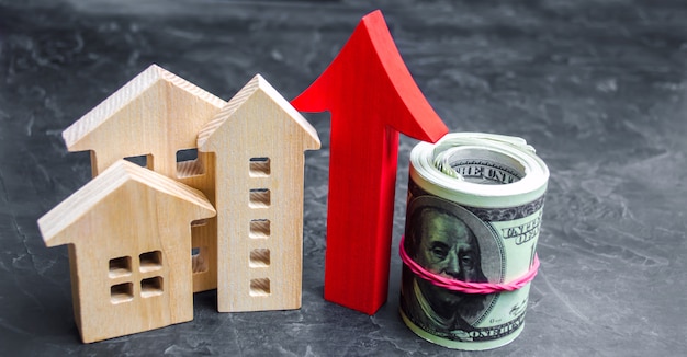 Photo wooden houses with a red arrow up. concept of high demand for real estate.