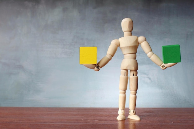 Wooden human figure balancing green and yellow wooden cube with copy space for text Harmony