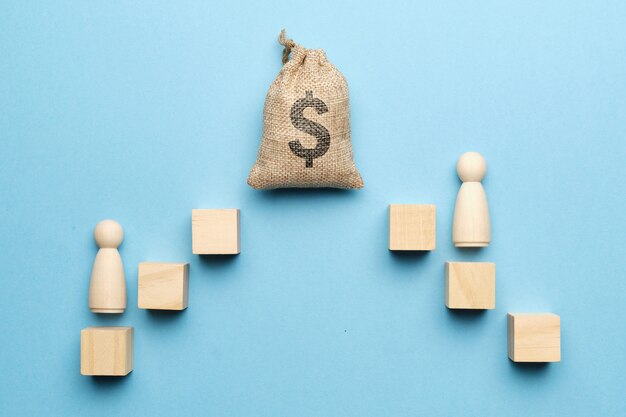 Wooden human figures on cubes next to sack of money