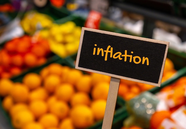 Segno di etichetta informativa in legno con testo inflazione contro il messaggio sfocato sugli scaffali dei negozi
