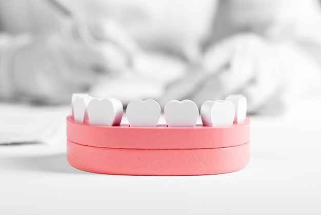 Wooden jaw model with teeth and dentist hands in background Dental health oral hygiene check for tooth disease stomatology concept