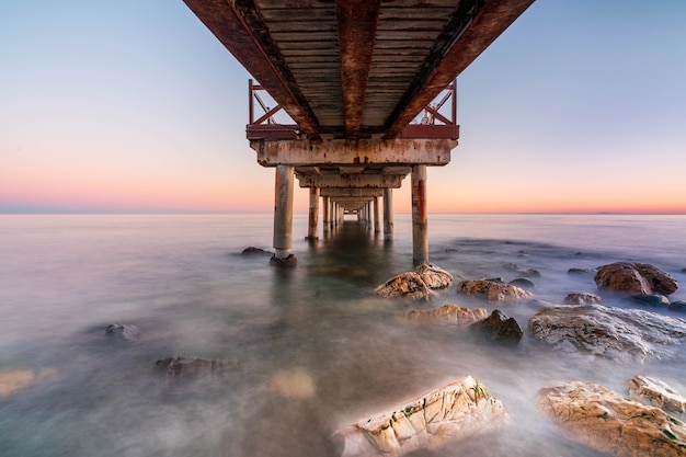 Wooden jetty on a beach at sunset