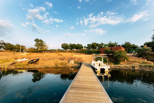 Wooden jetty with moored boat and reflections on lake water