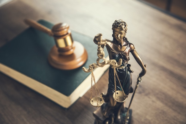 Wooden judge on book with justice lady on desk
