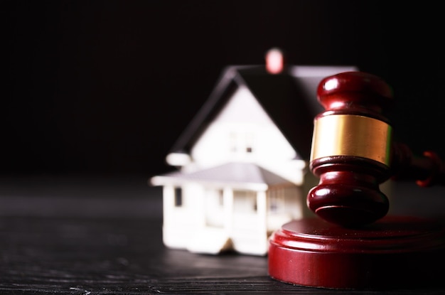 Wooden judge gavel and house on dark background