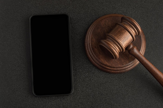 Wooden judge gavel and sound Board Black background next to smartphone Rights holders